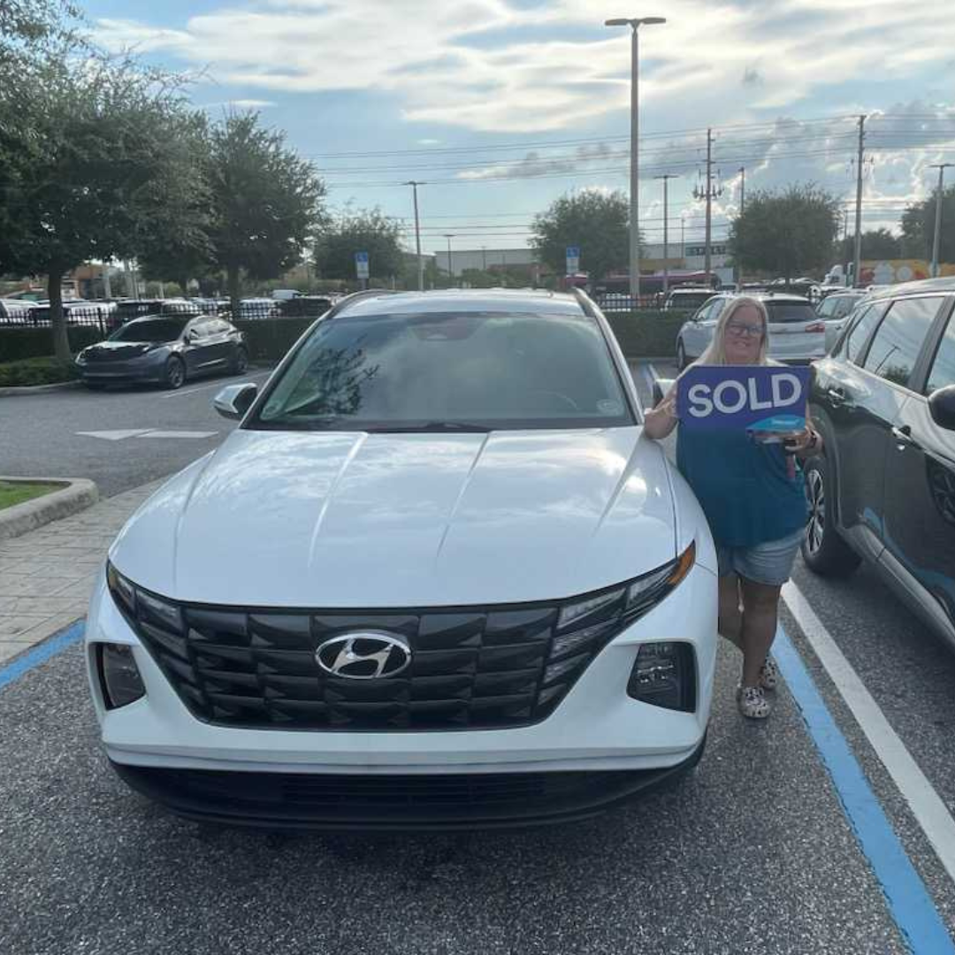 Person holding Sold Sign in front of vehicle