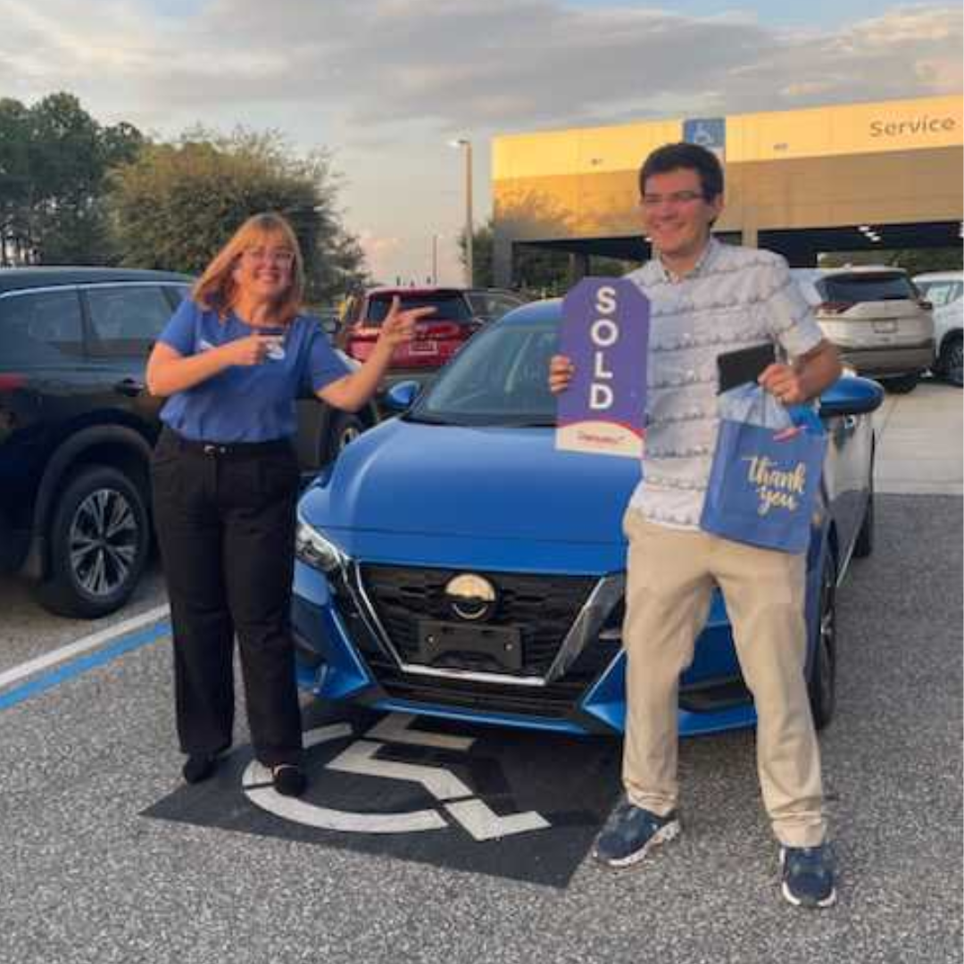 Person holding Sold Sign in front of vehicle