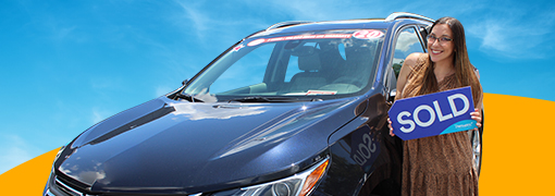 Person holding Sold sign by vehicle