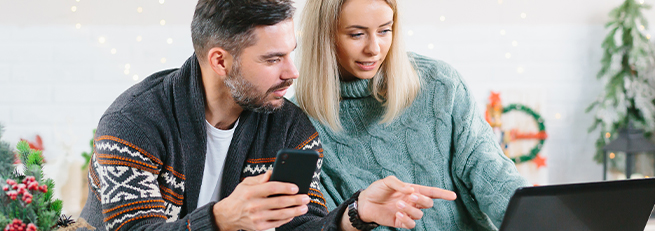 Male and female looking at phone and laptop